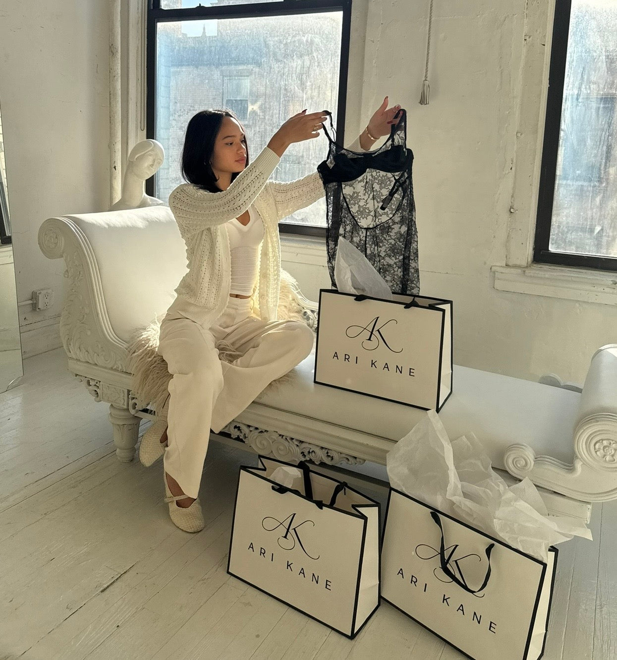 Ariana Kane holding a lace dress beside Ari Kane shopping bags